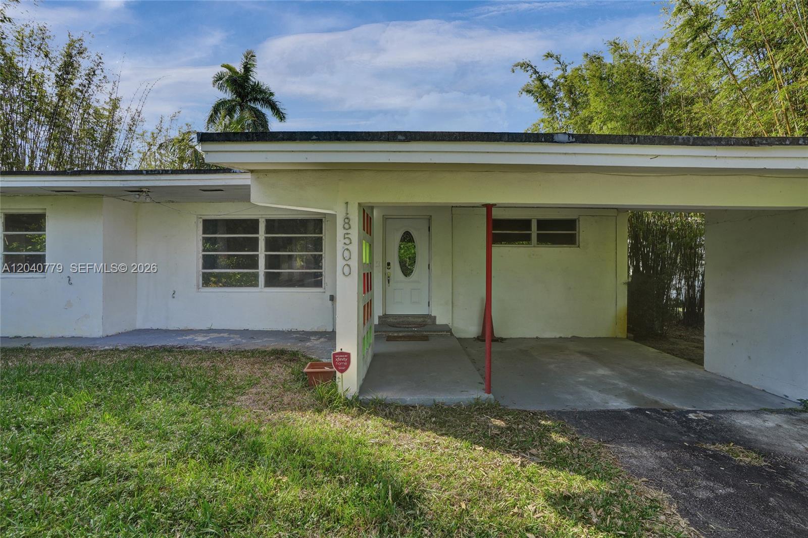 A single-story house features a white exterior, a carport, and a decorative screen block wall — 18500 NE 23rd Ct, Miami FL 33180, MIAMI, FL