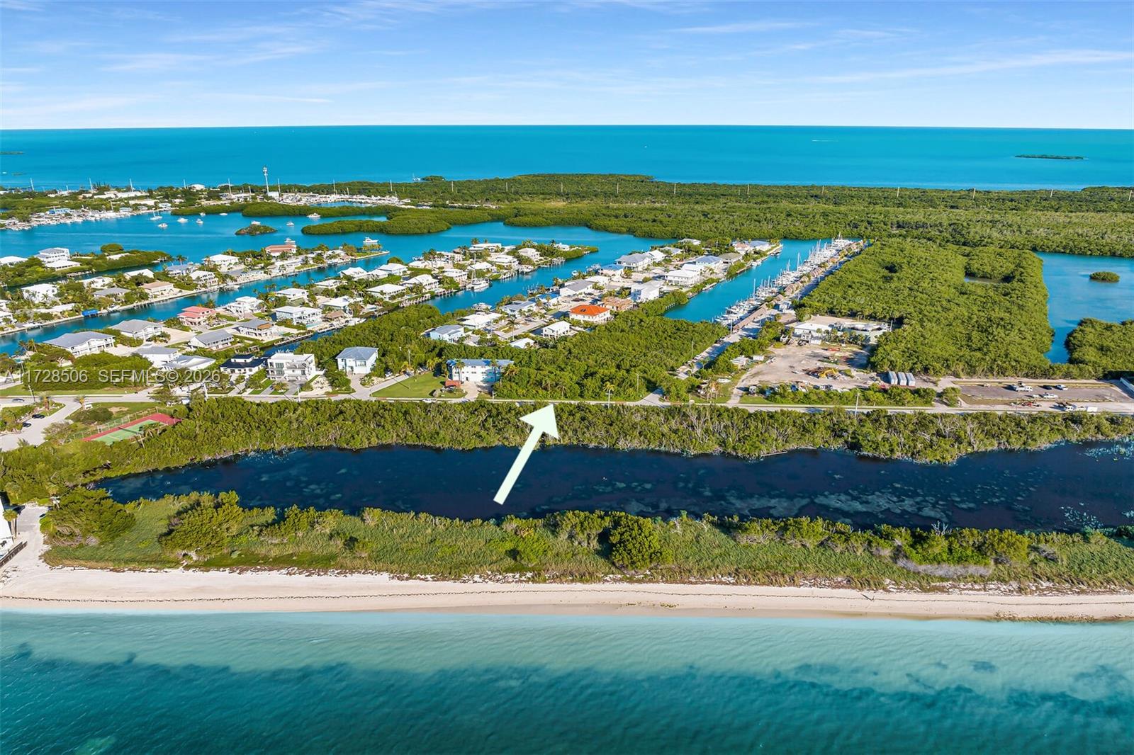 An aerial view shows a coastal neighborhood with a white arrow pointing toward a property — 300 Coco Plum, Marathon FL 33050, MARATHON, FL