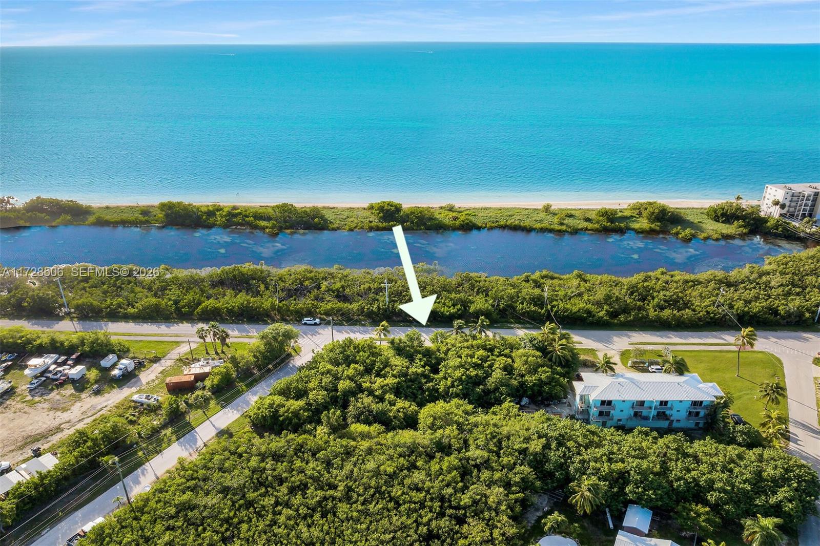 An aerial view shows a wooded lot located between a road and a coastal waterway — 300 Coco Plum, Marathon FL 33050, MARATHON, FL