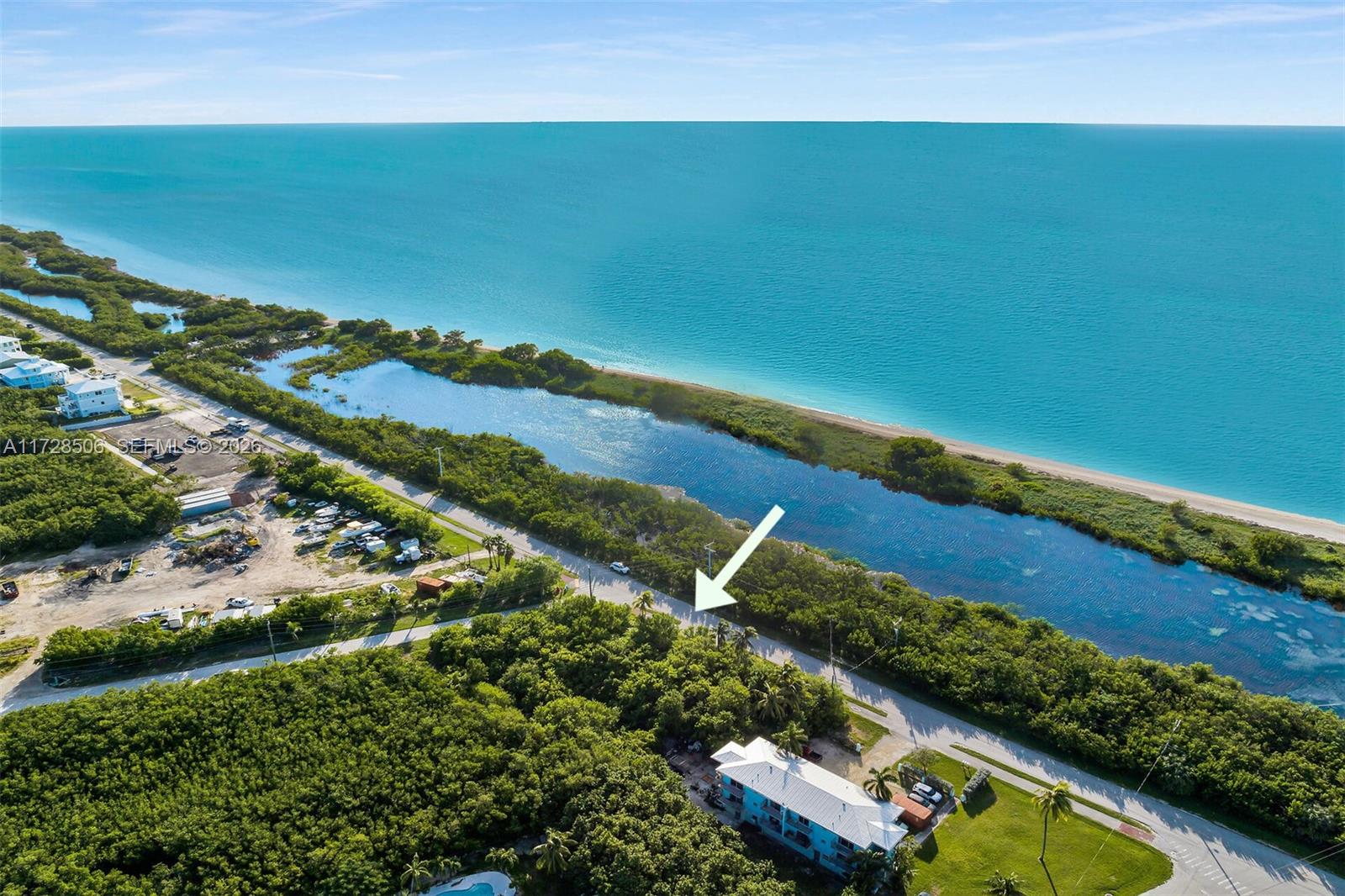 An aerial view shows a coastal road, a narrow waterway, and a blue house — 300 Coco Plum, Marathon FL 33050, MARATHON, FL
