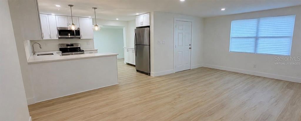 A kitchen with white cabinets and stainless steel appliances opens into a living area — 4533 W FERN STREET, TAMPA, FL