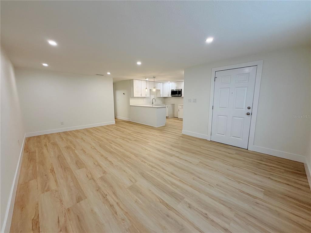 An open-concept living area features light wood-look flooring and a kitchen with white cabinets — 4533 W FERN STREET, TAMPA, FL