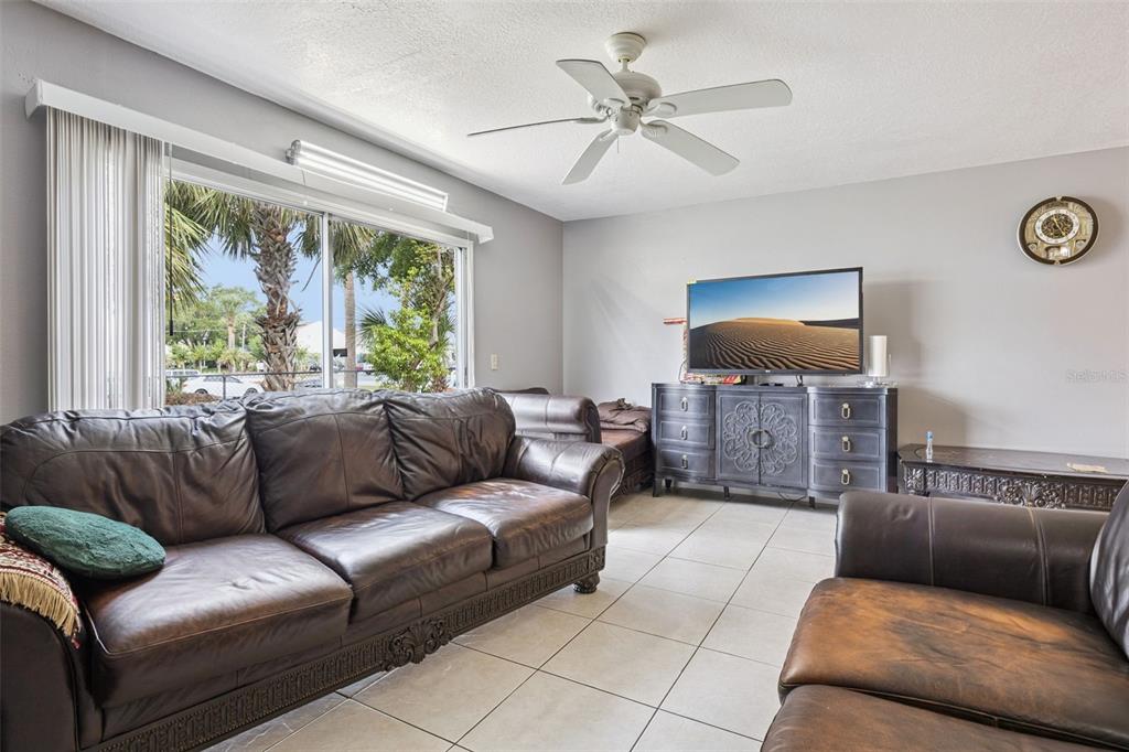 A living room features brown leather sofas, a television on a dark dresser, and tile flooring — 2460 SUMMERFIELD WAY, KISSIMMEE, FL