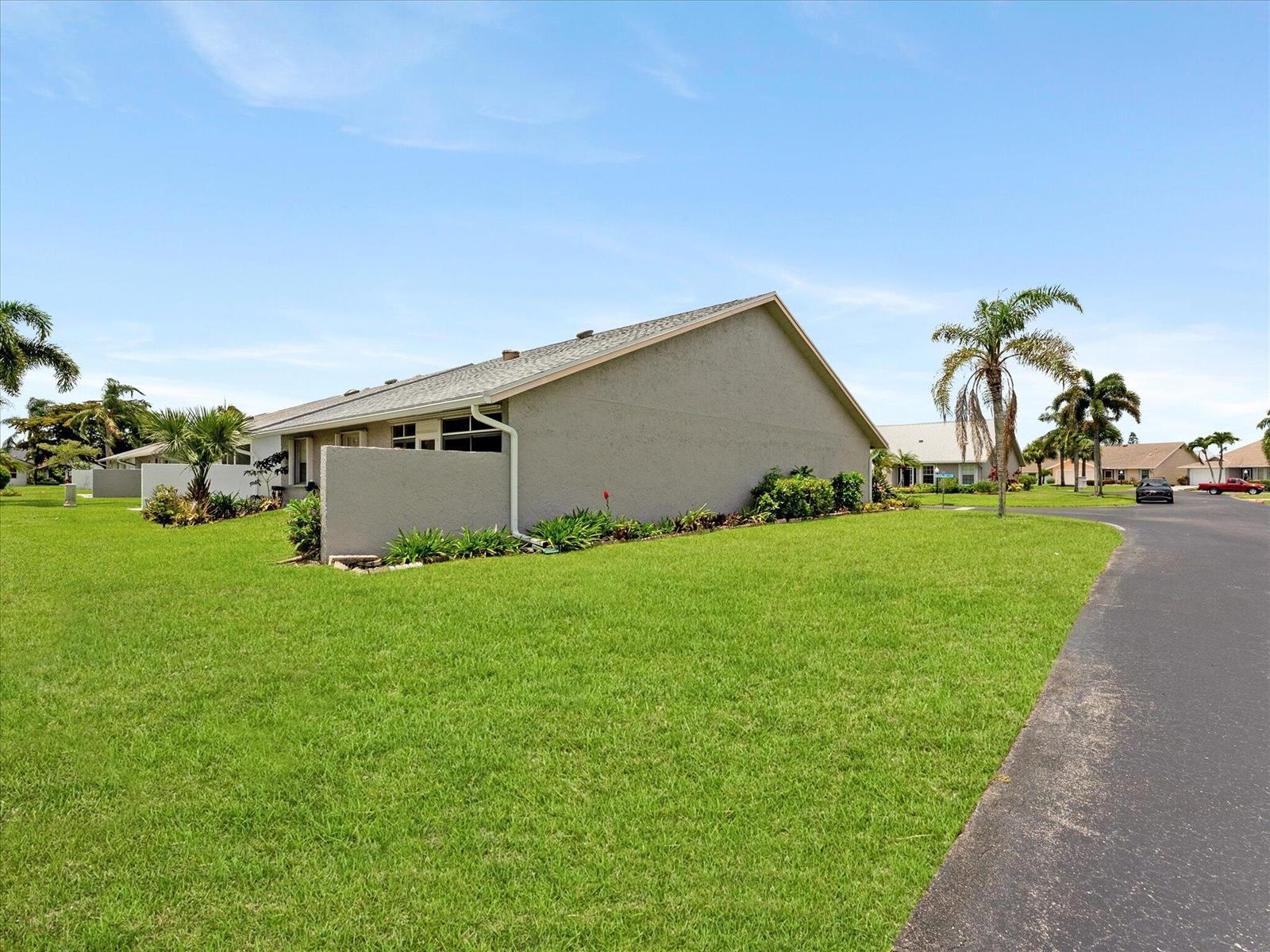 A side view of a single-story house with a grey stucco exterior and a lawn — 3897 Dafilee Circle, West Palm Beach FL 33417, WEST PALM BEACH, FL