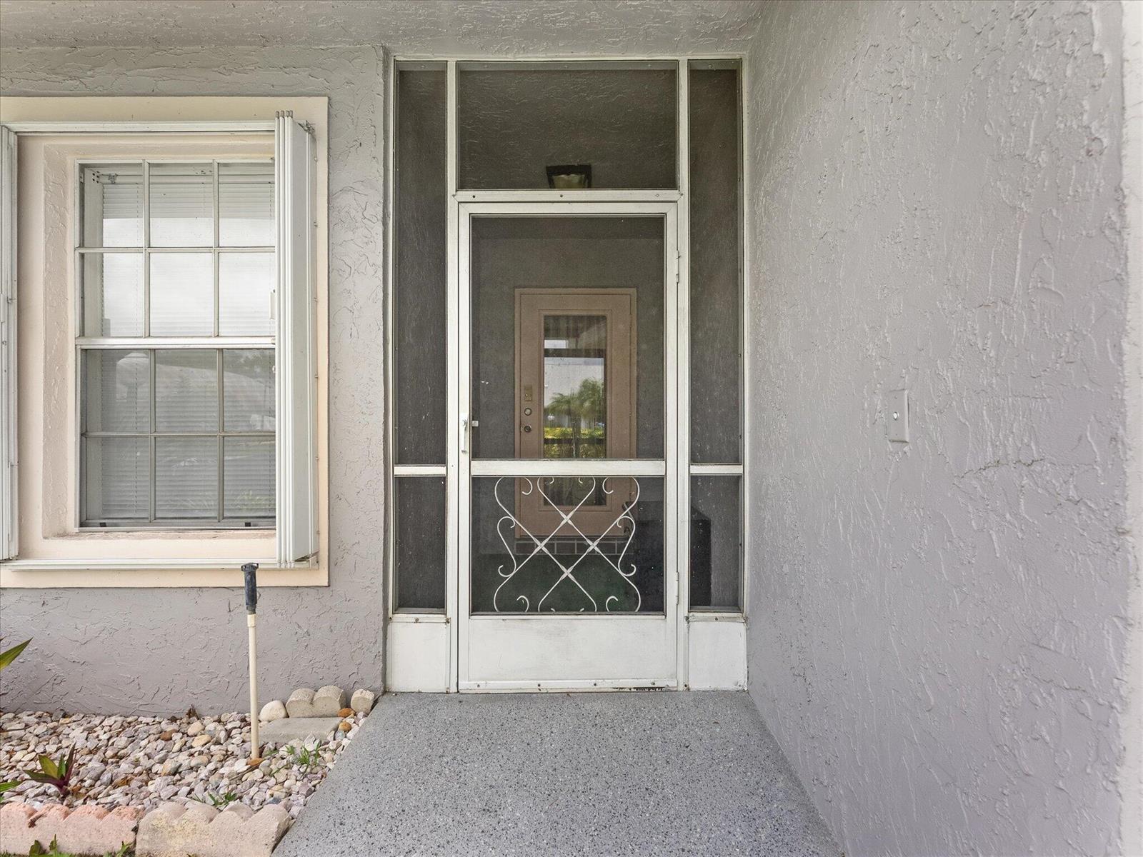 A white screen door with decorative metal scrollwork stands at the entrance of a home — 3897 Dafilee Circle, West Palm Beach FL 33417, WEST PALM BEACH, FL