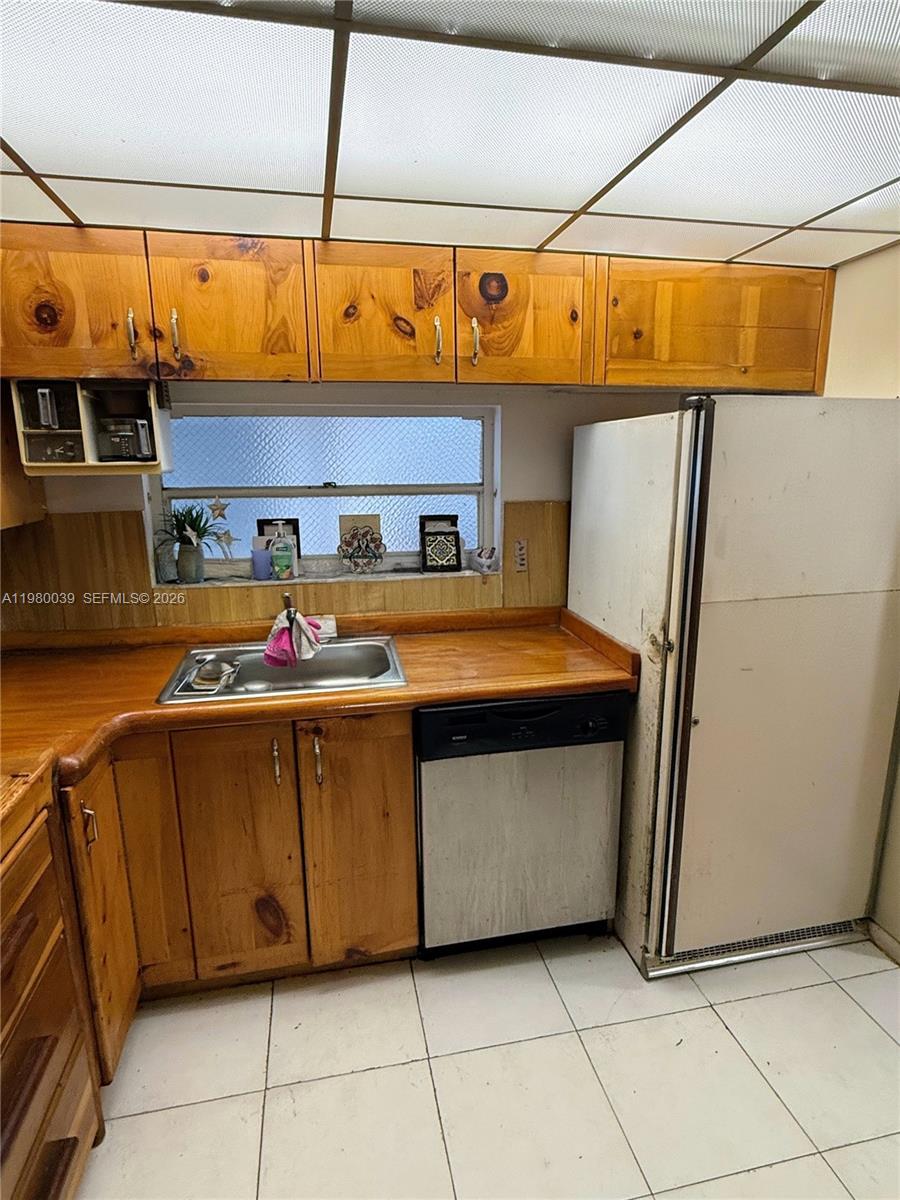 A kitchen features knotty pine cabinets, a stainless steel sink, and a white refrigerator — 100 Ocean Lane Dr # 303, Key Biscayne FL 33149, KEY BISCAYNE, FL