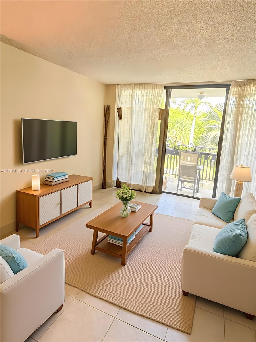 A living room features a television, a wooden coffee table, and a balcony view — 100 Ocean Lane Dr # 303, Key Biscayne FL 33149, KEY BISCAYNE, FL
