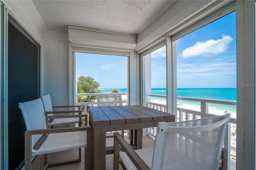 A balcony with a wooden table and chairs overlooks a beach and the ocean — 555 GULF WAY UNIT 6S, ST PETE BEACH, FL