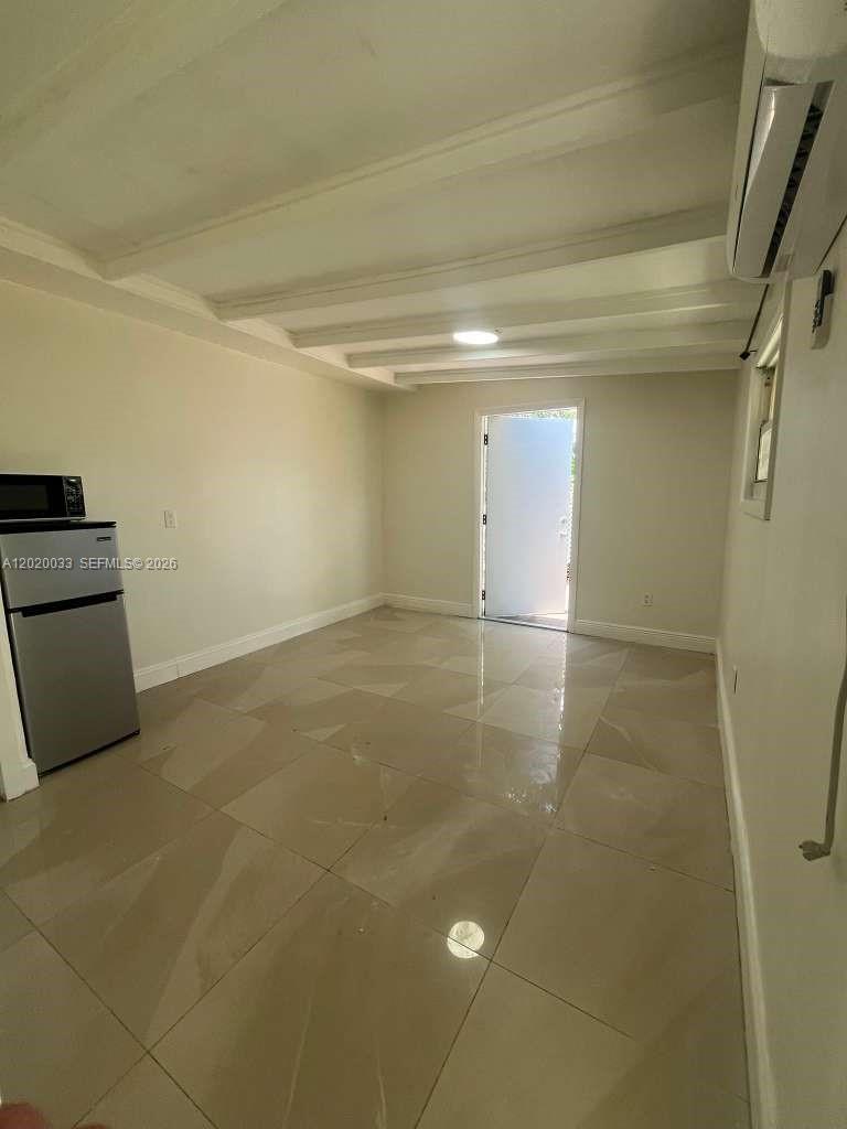 A small room features light-colored tile flooring, a white ceiling with beams, and a refrigerator — 1629 NE 177 ST # 2, Miami FL 33162, MIAMI, FL