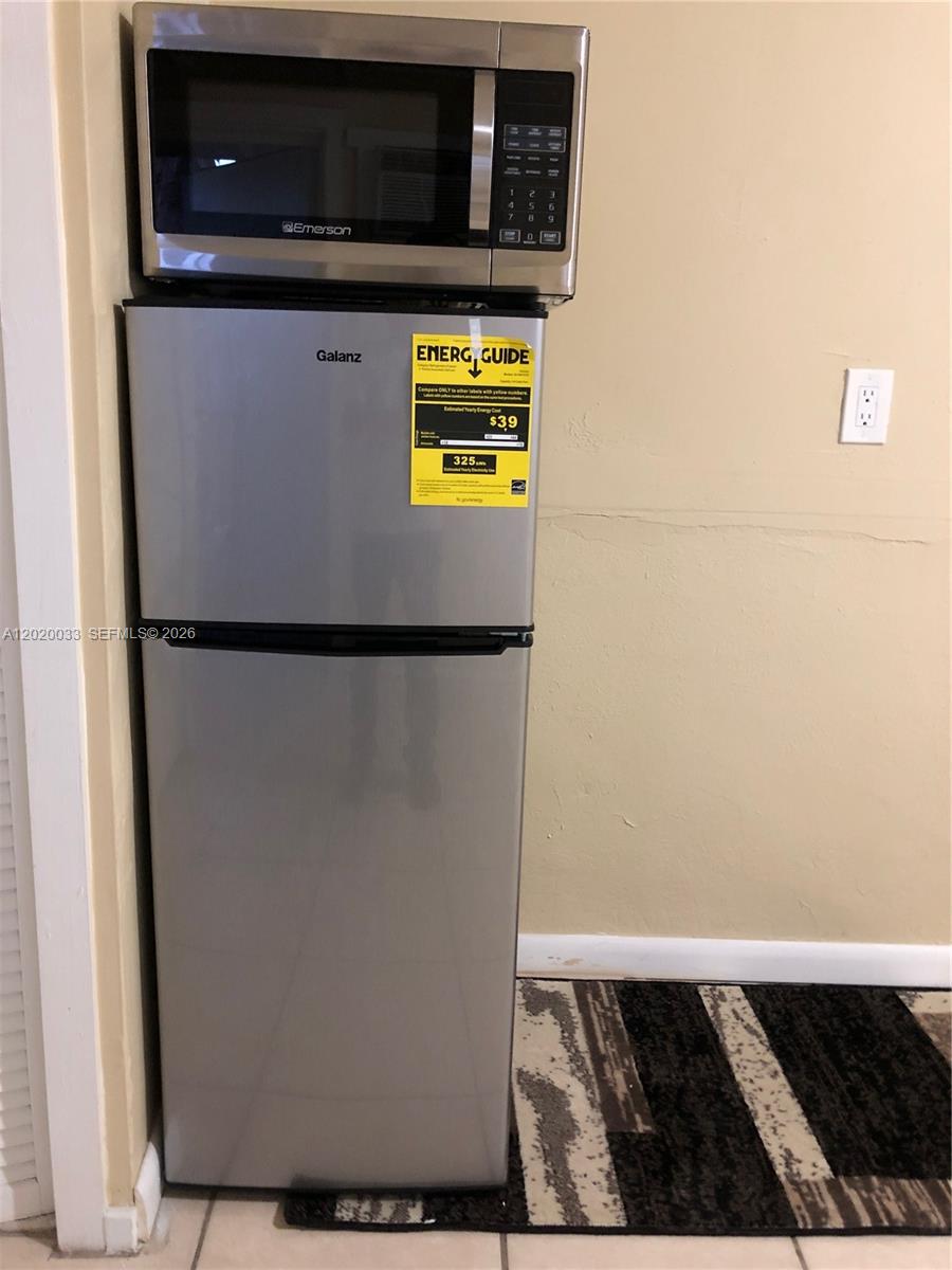 A stainless steel microwave sits atop a matching Galanz refrigerator in a room with beige walls — 1629 NE 177 ST # 2, Miami FL 33162, MIAMI, FL