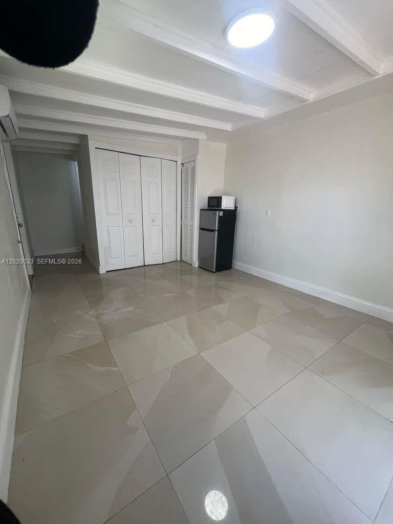 A room with light-colored tile flooring, white walls, a closet, and a small refrigerator — 1629 NE 177 ST # 2, Miami FL 33162, MIAMI, FL