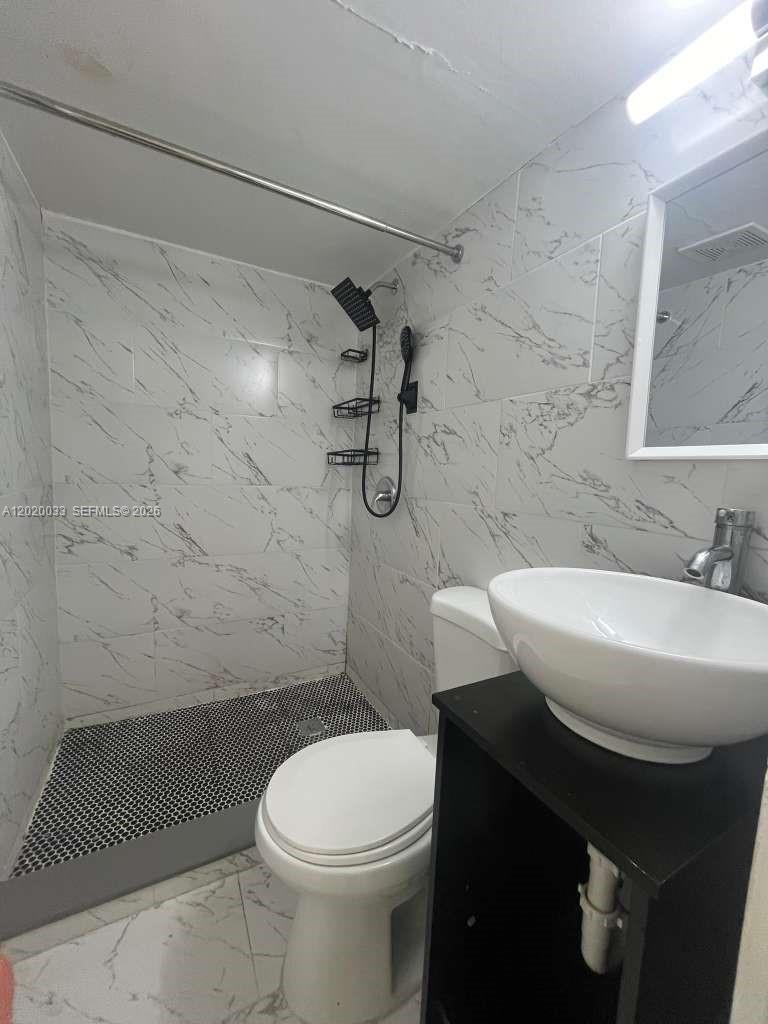 A bathroom features a walk-in shower with marble-look tile, a toilet, and a vessel sink — 1629 NE 177 ST # 2, Miami FL 33162, MIAMI, FL