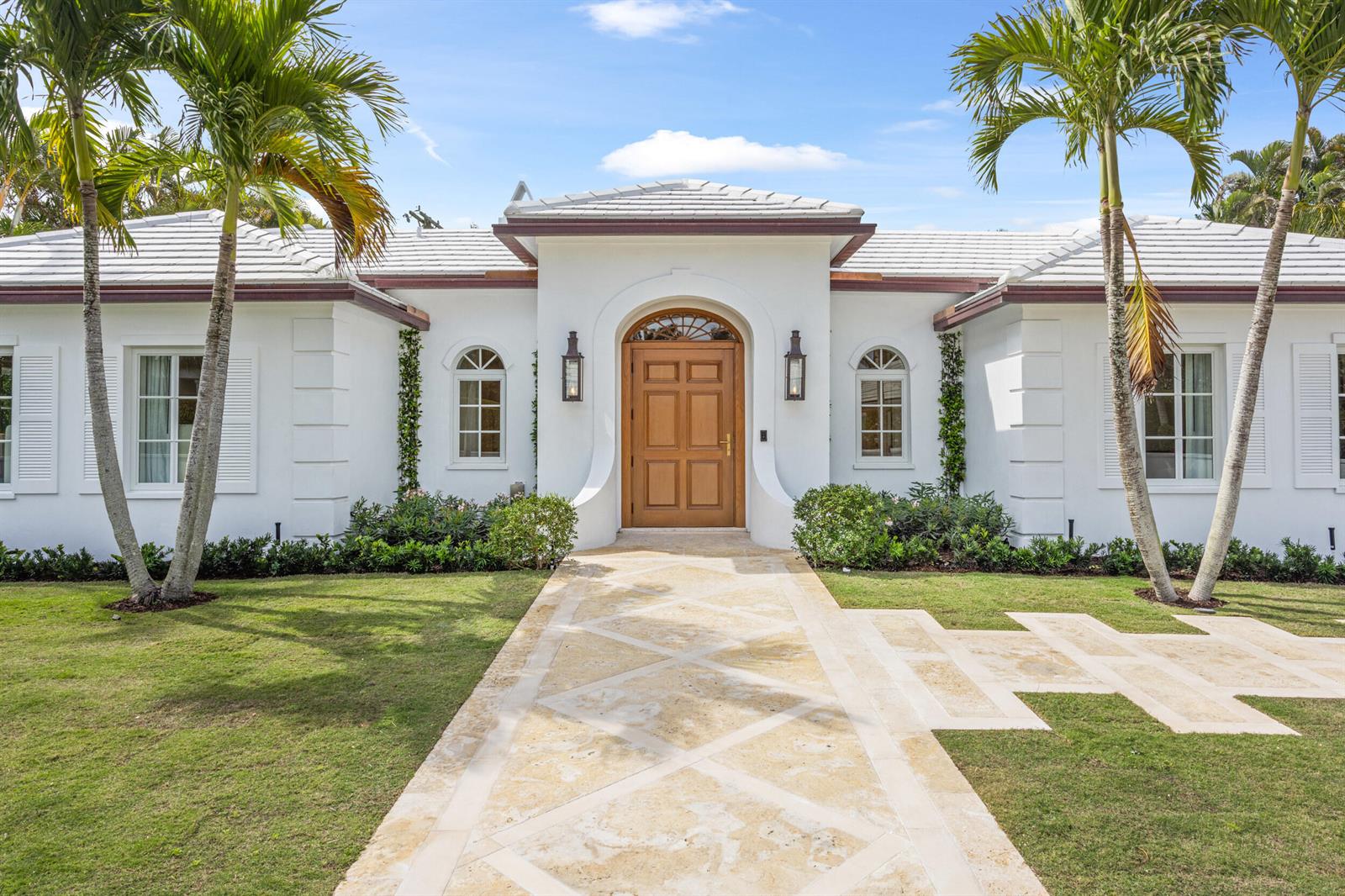 A white single-story house features a wooden front door, arched windows, and palm trees — 224 Southland Road, Palm Beach FL 33480, PALM BEACH, FL