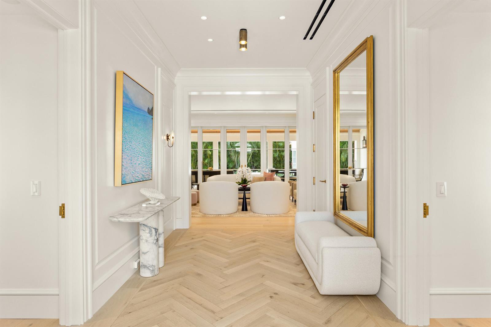 A bright entryway features herringbone wood floors, a marble console table, and a large mirror — 224 Southland Road, Palm Beach FL 33480, PALM BEACH, FL
