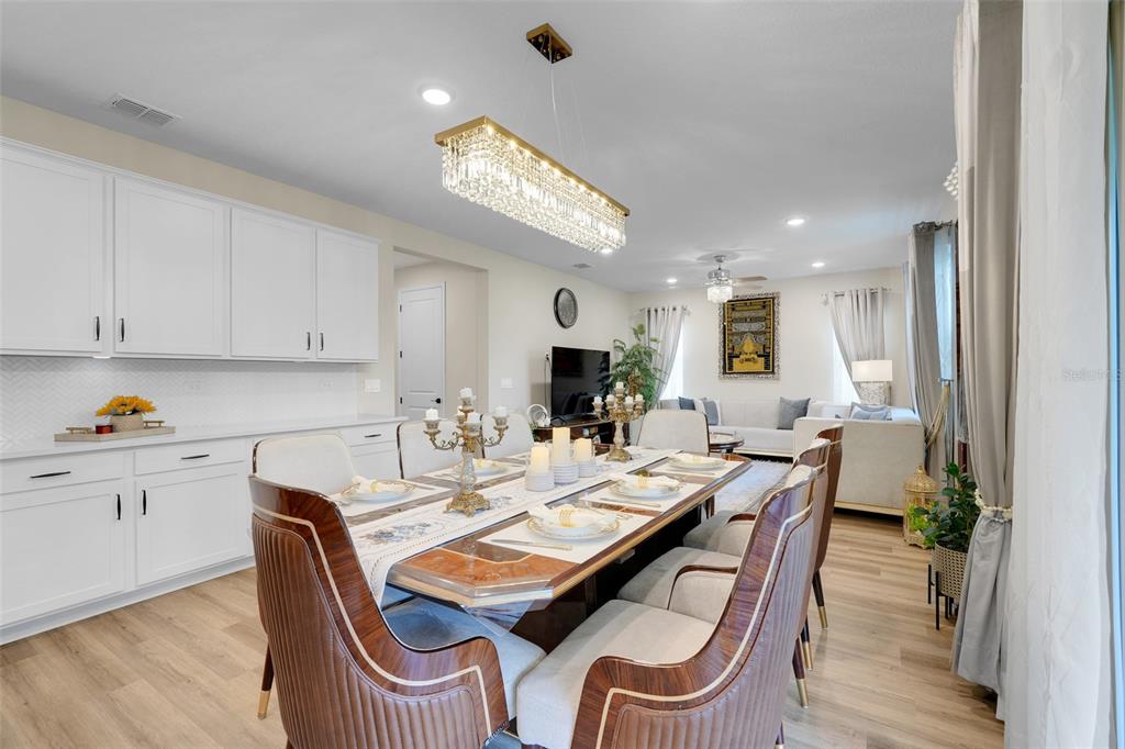 A dining room with a long wooden table, upholstered chairs, and a crystal chandelier — 10169 SPRING LAKE DRIVE, CLERMONT, FL