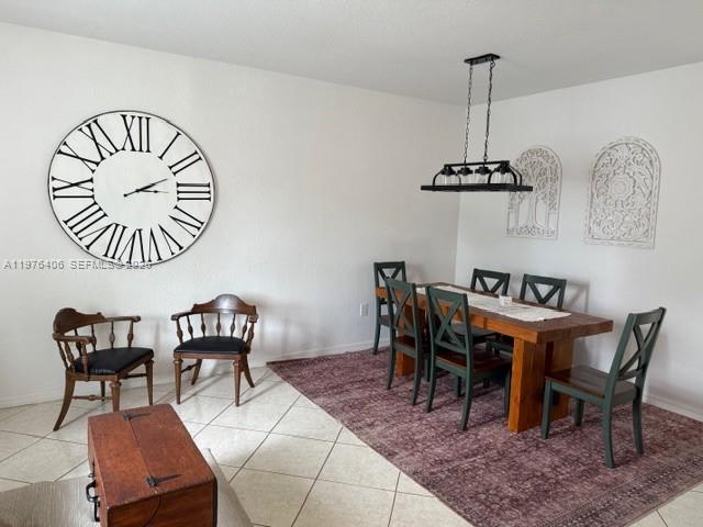 A dining room features a large wall clock, a wooden table, and a dark rug — 5737 NW 114th Path # 113, Doral FL 33178, DORAL, FL