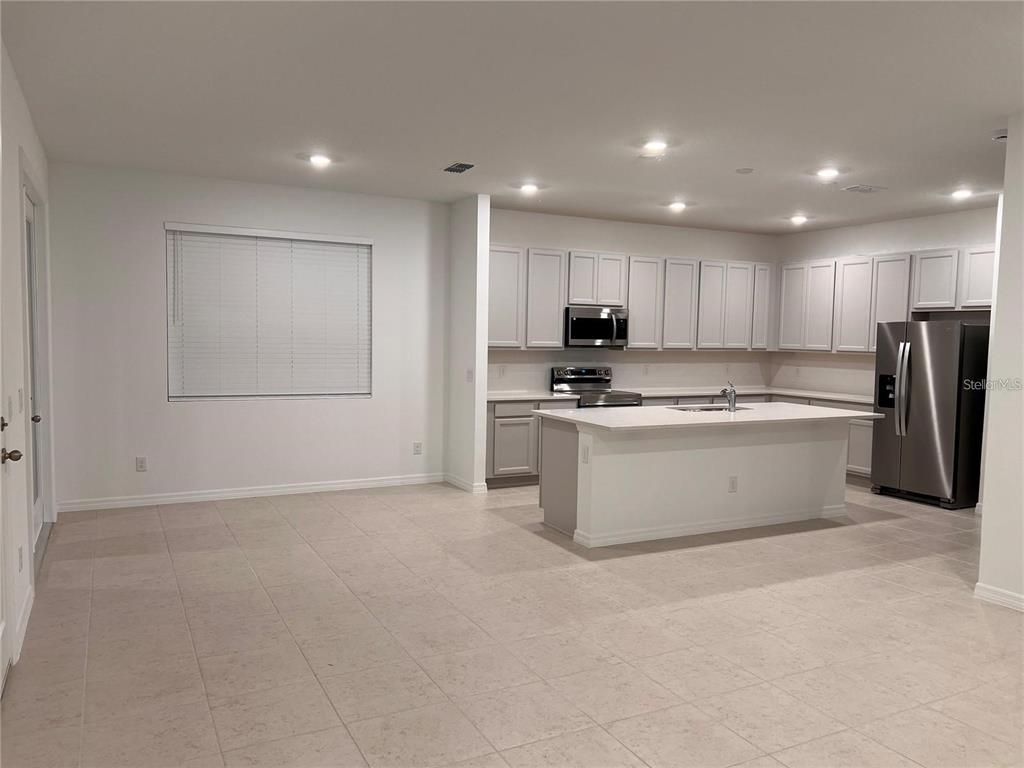 A kitchen with light gray cabinets, a white island, and tile flooring — 17820 SHARP PUMMELO ALLEY, WINTER GARDEN, FL