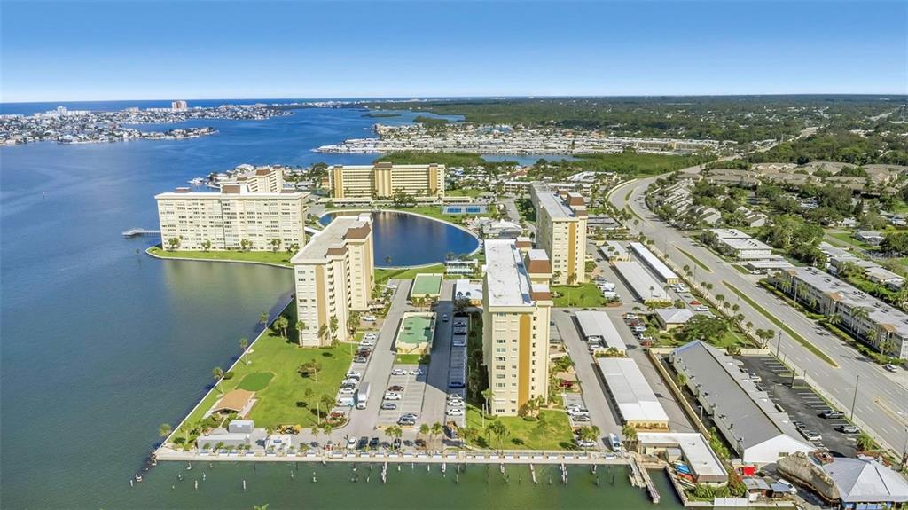 An aerial view shows several high-rise apartment buildings situated on a peninsula near water — 4700 COVE CIRCLE UNIT 107, ST PETERSBURG, FL