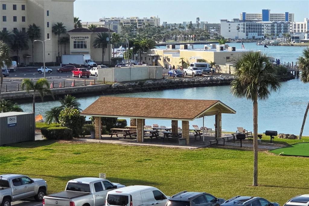 An outdoor pavilion with picnic tables sits on a lawn near a waterfront parking lot — 4700 COVE CIRCLE UNIT 107, ST PETERSBURG, FL
