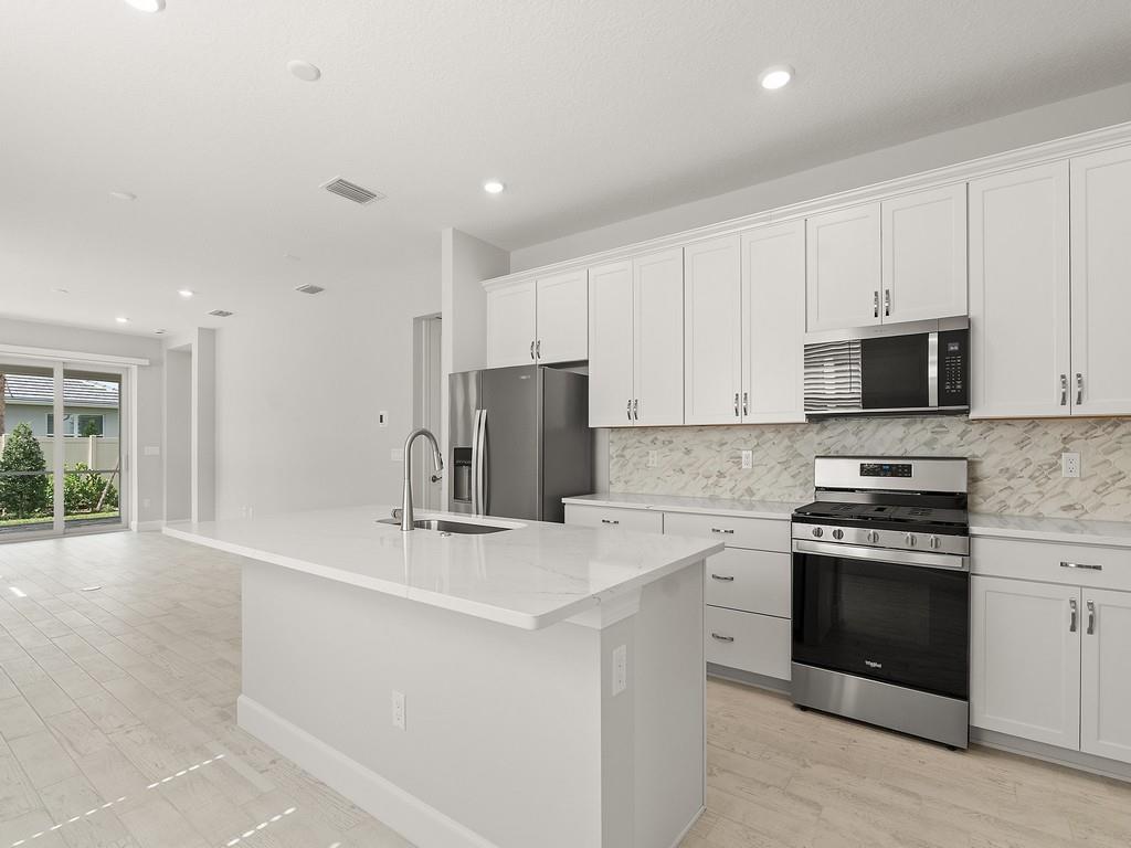 A modern kitchen features white cabinetry, stainless steel appliances, and a central quartz island — 4501 Nautilus Circle, Vero Beach FL 32967, VERO BEACH, FL