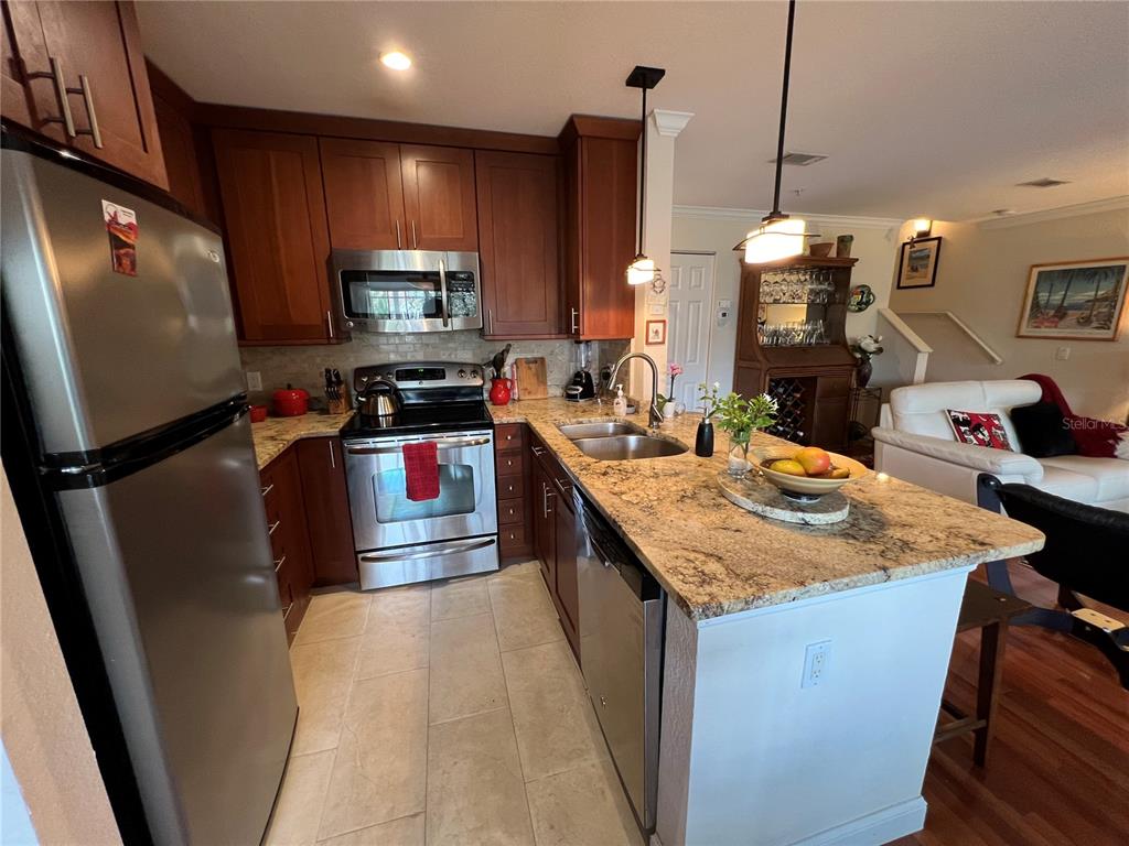A kitchen with wood cabinets, granite countertops, stainless steel appliances, and a central island — 850 S TAMIAMI TRAIL UNIT 333, SARASOTA, FL