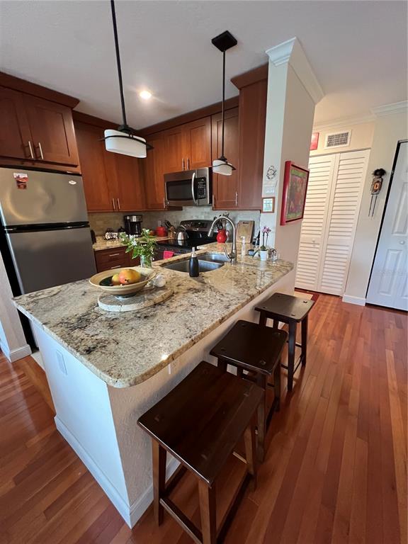 A kitchen features wood cabinets, granite countertops, a stainless steel refrigerator, and three bar stools — 850 S TAMIAMI TRAIL UNIT 333, SARASOTA, FL