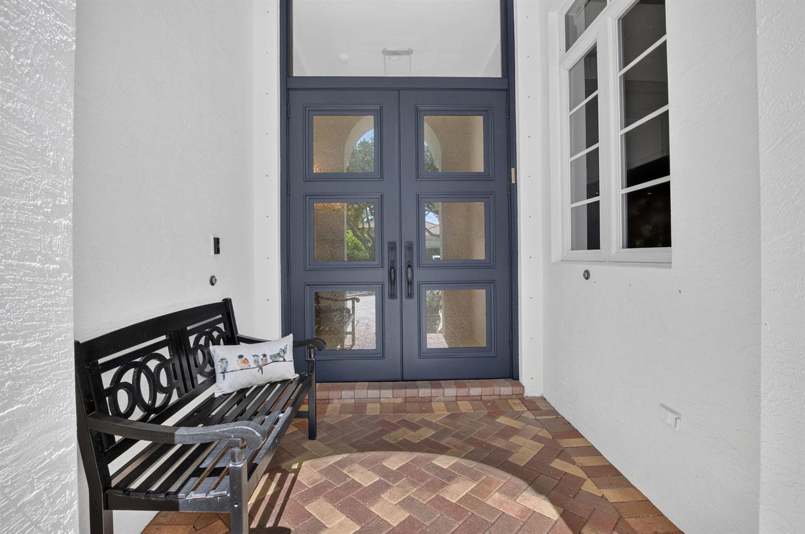 A black bench sits on a brick porch in front of a dark blue double door — 17936 Villa Club Way, Boca Raton FL 33496, BOCA RATON, FL
