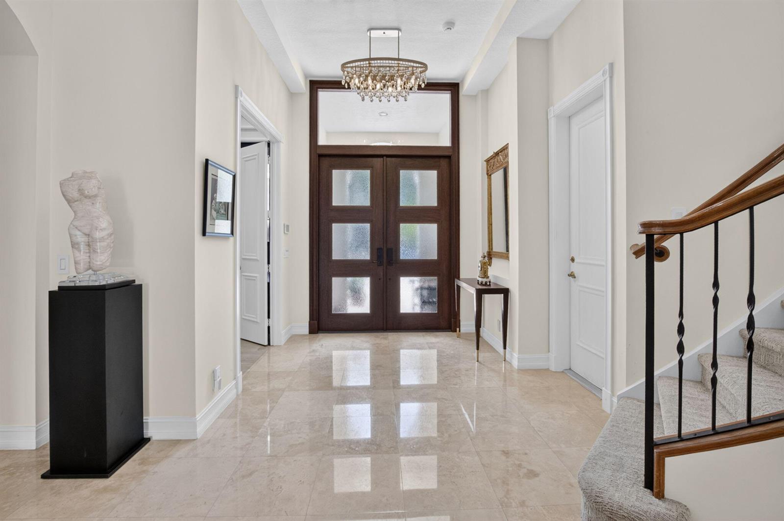 A bright foyer features marble floors, a crystal chandelier, and a dark wood double door — 17936 Villa Club Way, Boca Raton FL 33496, BOCA RATON, FL