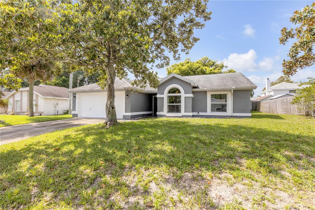 A single-story gray house with a white garage door and a large front yard tree — 886 ANDKEN LANE, PORT ORANGE, FL