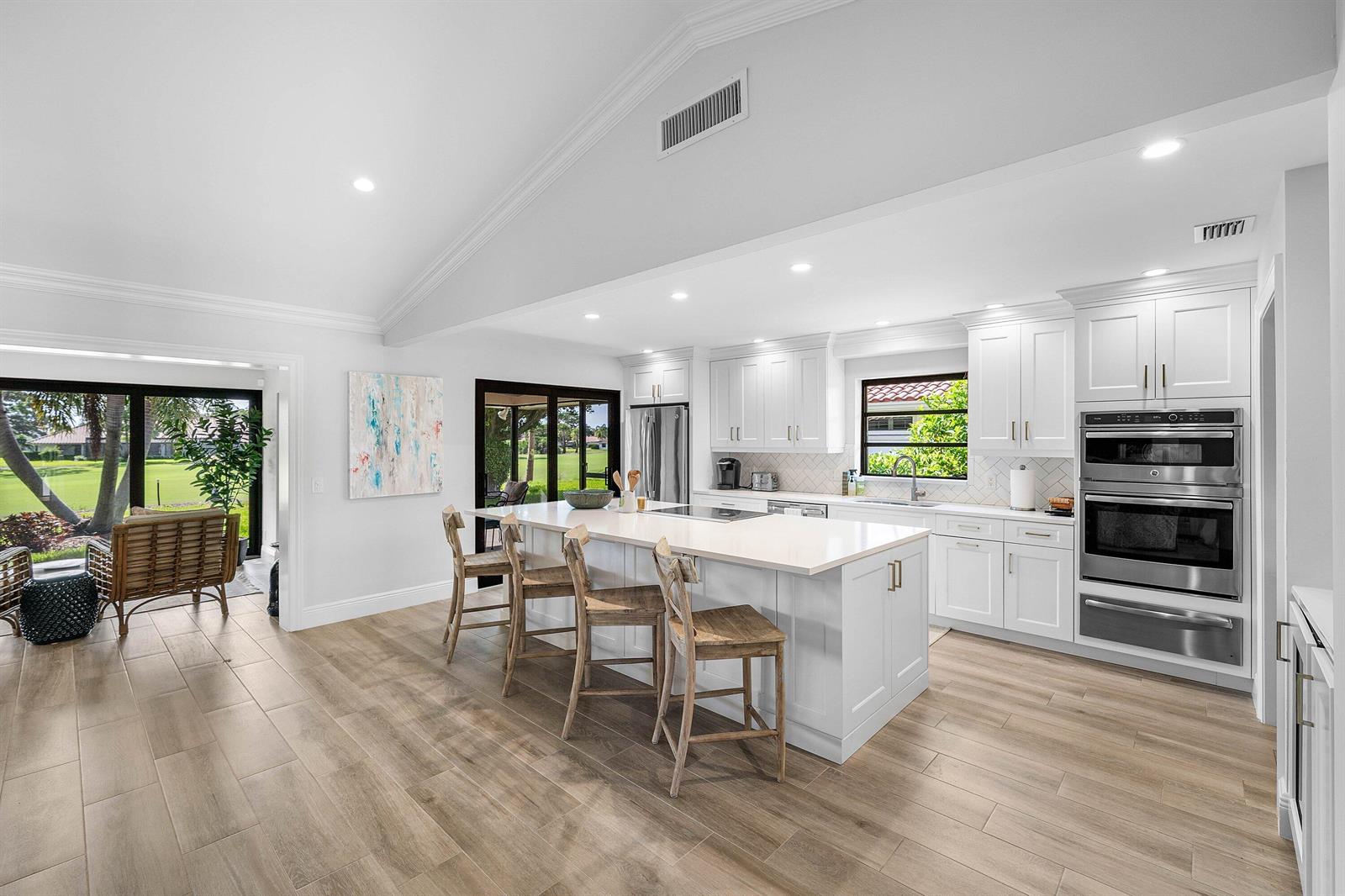 A bright kitchen with white cabinetry, a large island, and wood-look tile flooring — 10420 Seaholly Terrace, Boynton Beach FL 33436, BOYNTON BEACH, FL