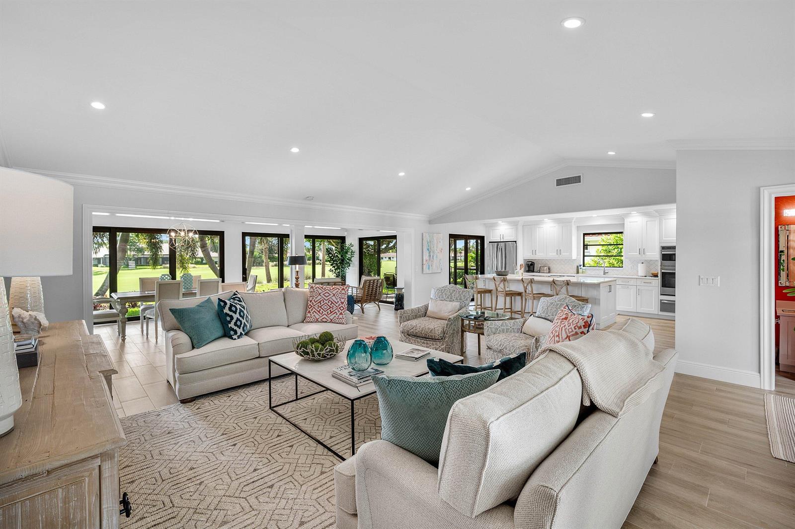 An open-concept living room and kitchen with light wood floors and large glass doors — 10420 Seaholly Terrace, Boynton Beach FL 33436, BOYNTON BEACH, FL
