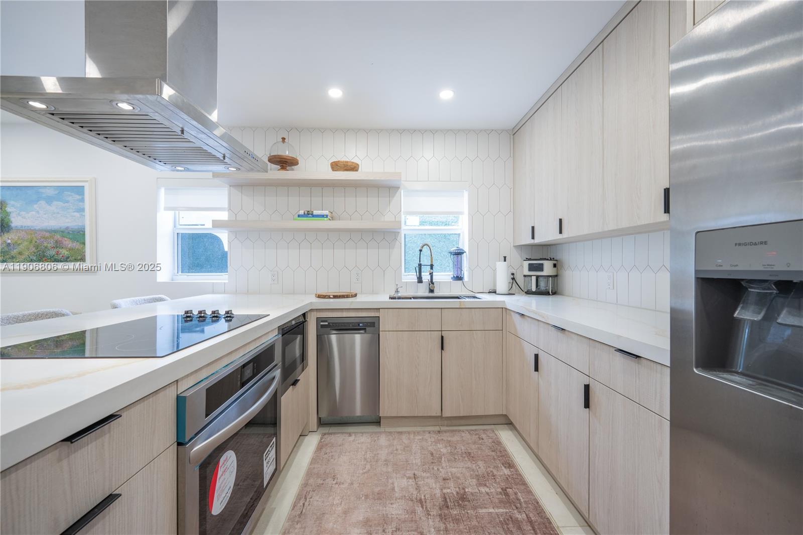 A modern kitchen features light wood cabinets, stainless steel appliances, and white tiled walls — 545 NW 47th St, Miami FL 33127, MIAMI, FL