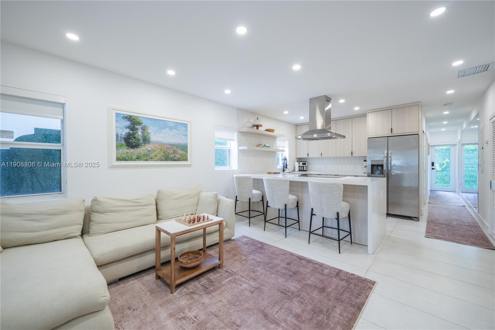 A modern open-concept kitchen and living area features light wood cabinetry and a white sofa — 545 NW 47th St, Miami FL 33127, MIAMI, FL