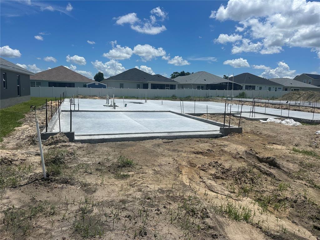 A concrete foundation slab for a new home construction site under a blue sky — 12601 NE 48TH STREET, OXFORD, FL