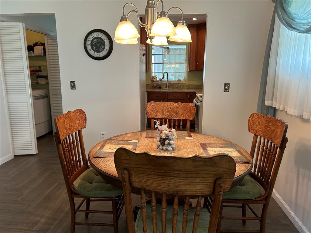 A dining area features a round wooden table with four chairs and a kitchen beyond — 1359 GLENDALE CIRCLE W UNIT 214, SARASOTA, FL
