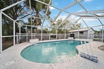 An outdoor swimming pool is enclosed by a white screen cage with a concrete deck — 344 50TH STREET W, PALMETTO, FL