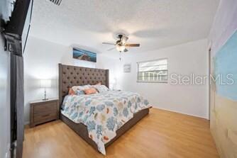 A bedroom features a tufted headboard, a patterned bedspread, a ceiling fan, and wood flooring — 344 50TH STREET W, PALMETTO, FL