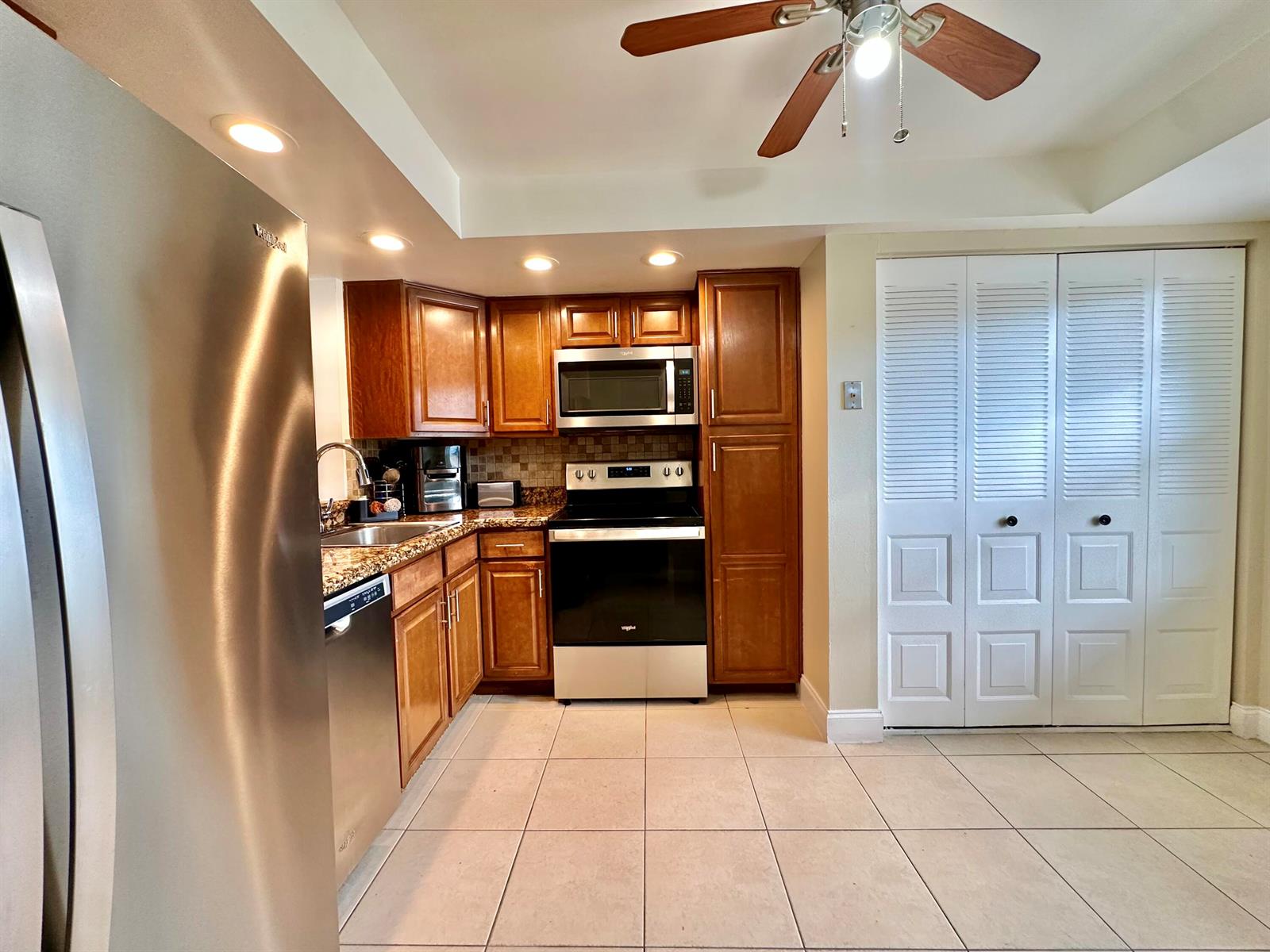 A kitchen features wooden cabinets, stainless steel appliances, tile flooring, and a ceiling fan — 1650 NW 80th Avenue, Margate FL 33063, MARGATE, FL