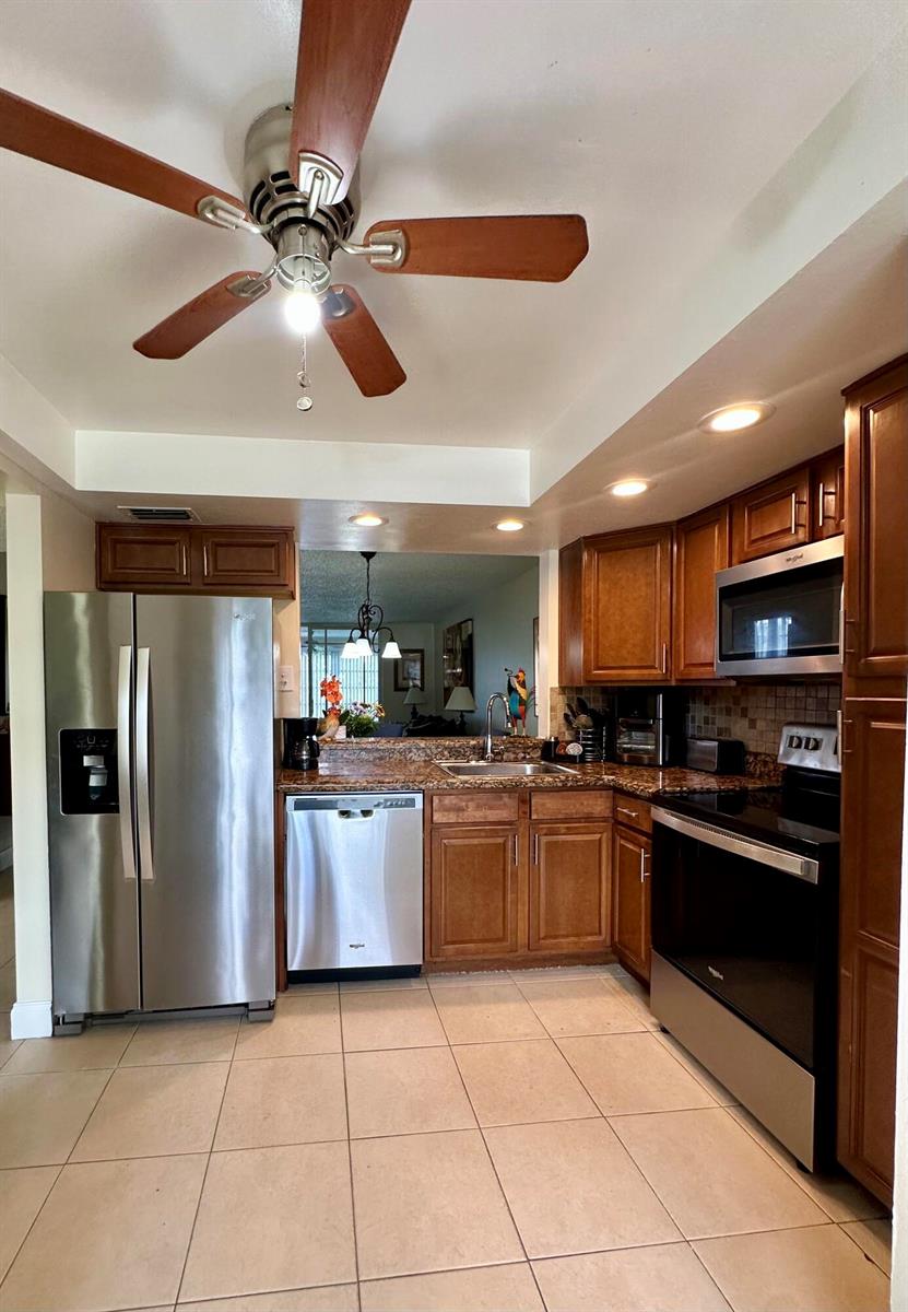 A kitchen features wood cabinets, stainless steel appliances, granite countertops, and tile flooring — 1650 NW 80th Avenue, Margate FL 33063, MARGATE, FL