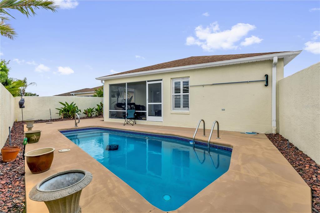 A backyard features a swimming pool with a metal ladder next to a house — 1214 SAN BERNARDO ROAD, THE VILLAGES, FL