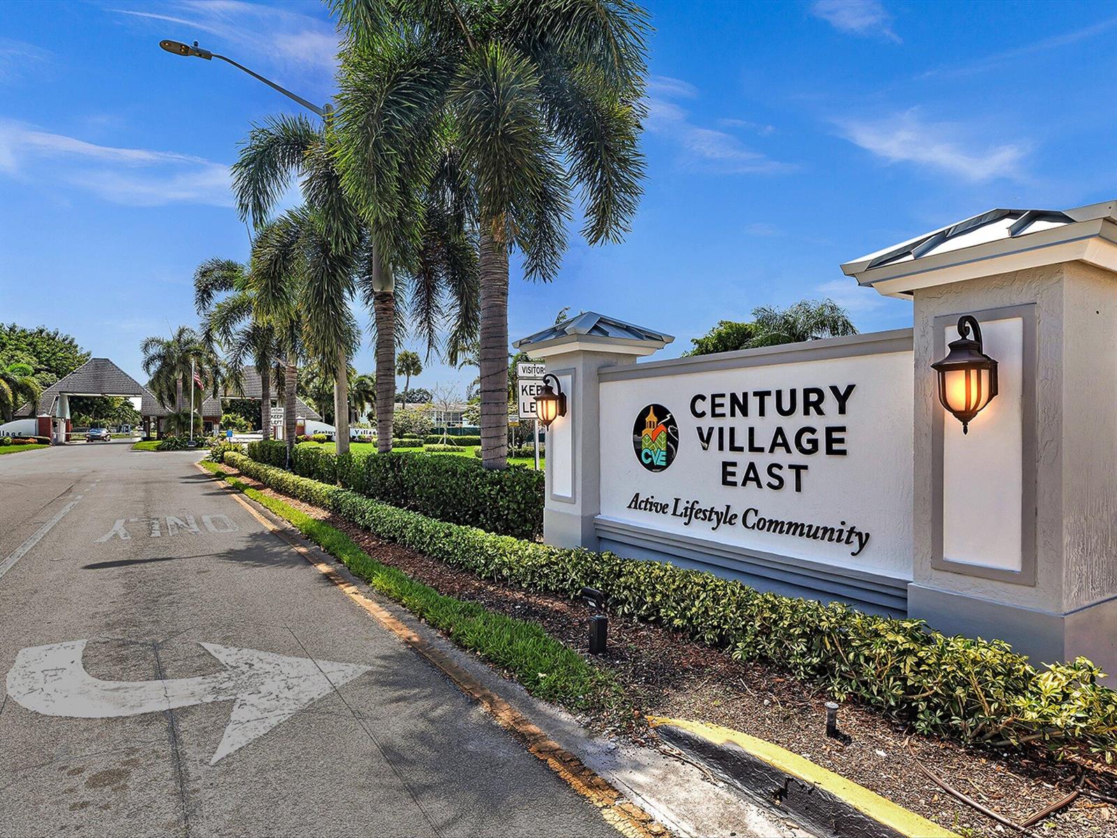 A sign for Century Village East stands beside a palm-lined road with a gated entrance — 5 Markham A, Deerfield Beach FL 33442, DEERFIELD BEACH, FL