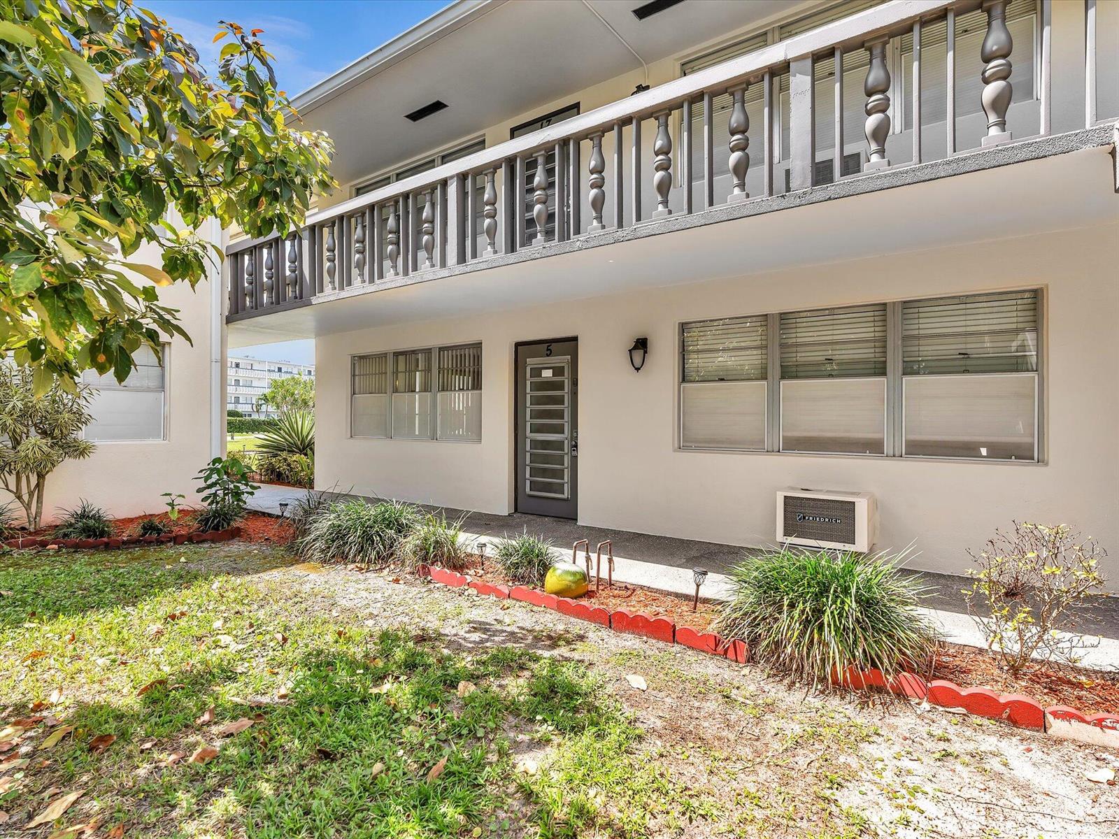 The exterior of a two-story apartment building features a balcony, a ground-floor entrance, and landscaping — 5 Markham A, Deerfield Beach FL 33442, DEERFIELD BEACH, FL