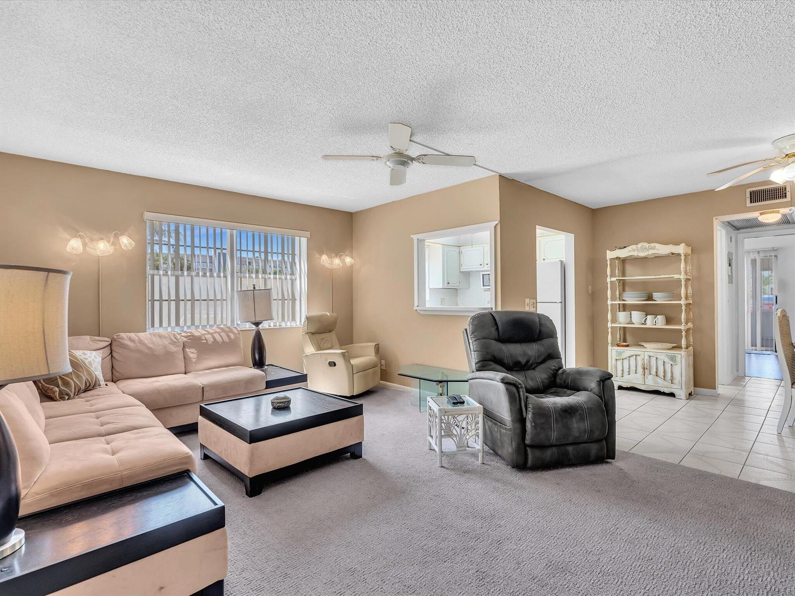 A living room featuring a beige sectional, a dark recliner, and a pass-through kitchen window — 5 Markham A, Deerfield Beach FL 33442, DEERFIELD BEACH, FL