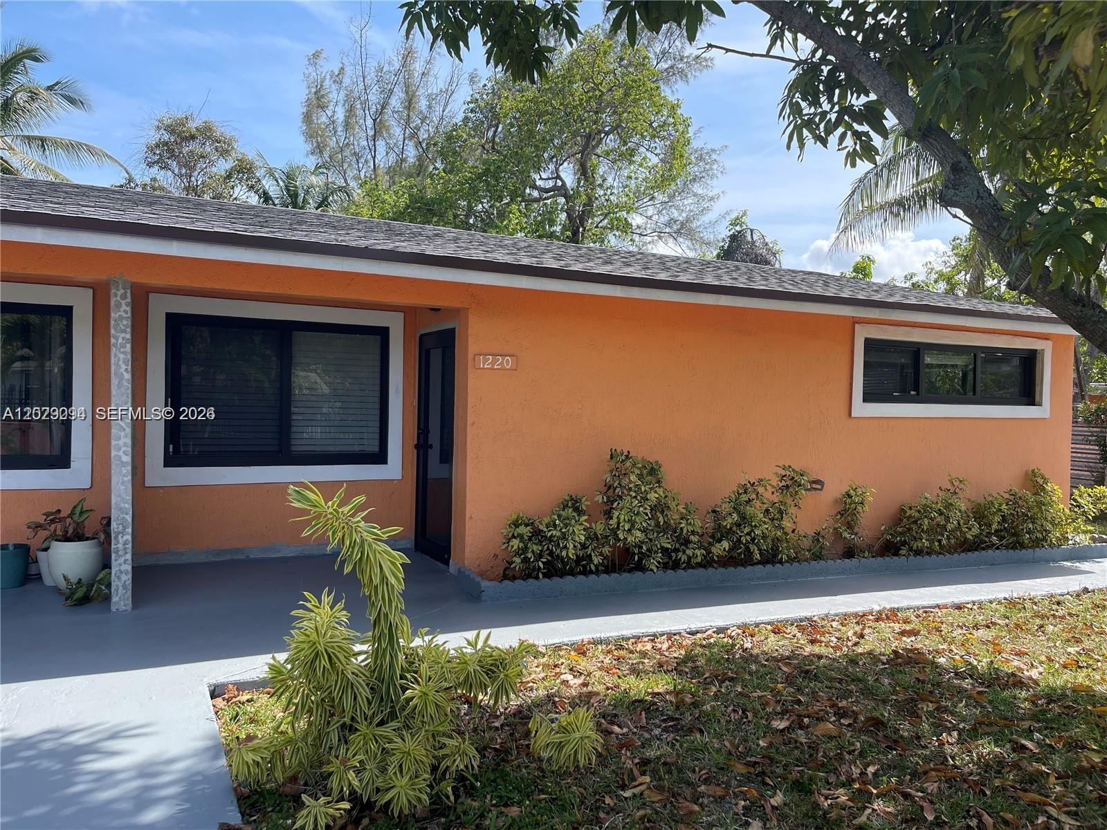 An orange exterior wall features a front door, two windows, and a gray concrete porch — 1220 NE 116th St # 1222, Miami FL 33161, MIAMI, FL
