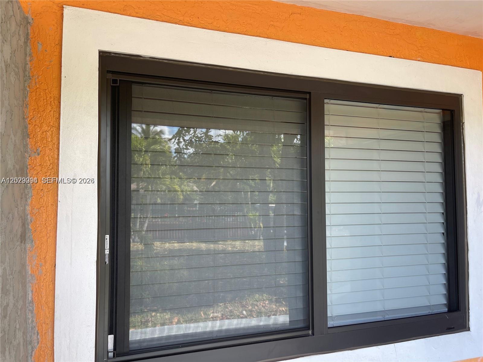 A dark-framed window with blinds is set into a wall with orange and white trim — 1220 NE 116th St # 1222, Miami FL 33161, MIAMI, FL