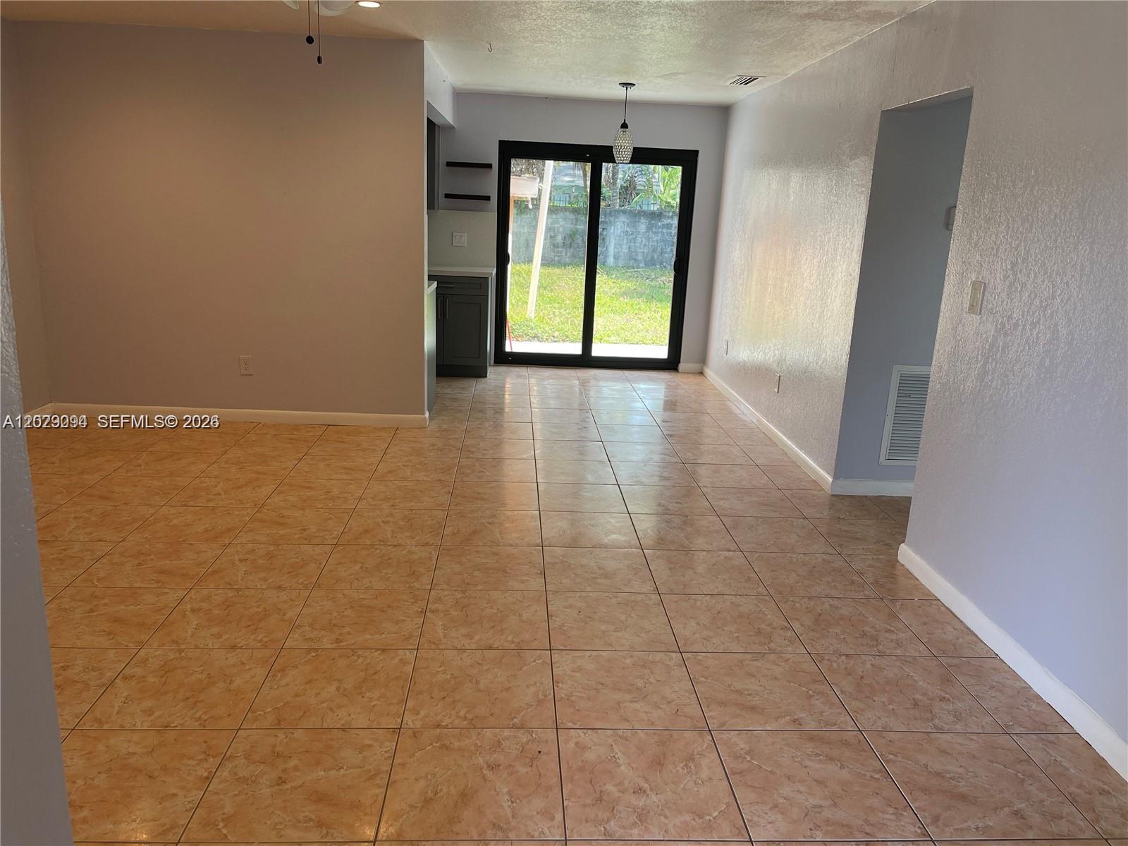 A room with light-colored tile flooring, gray walls, and a sliding glass door to outside — 1220 NE 116th St # 1222, Miami FL 33161, MIAMI, FL