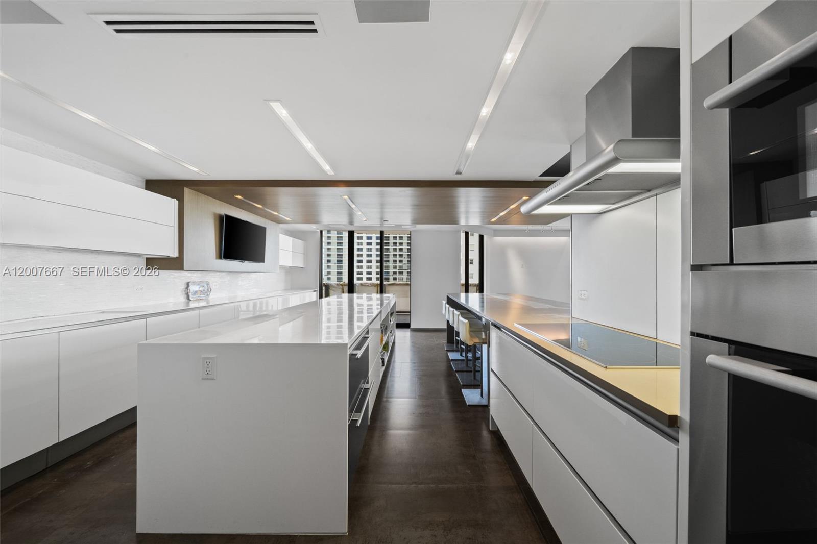A modern kitchen features a large white island, sleek cabinetry, and dark tiled flooring — 9999 Collins Ave # 6J, Bal Harbour FL 33154, BAL HARBOUR, FL