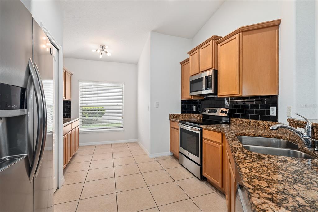 A kitchen with wood cabinets, granite countertops, stainless steel appliances, and a tiled floor — 5317 PEACH BLOSSOM BOULEVARD, PORT ORANGE, FL