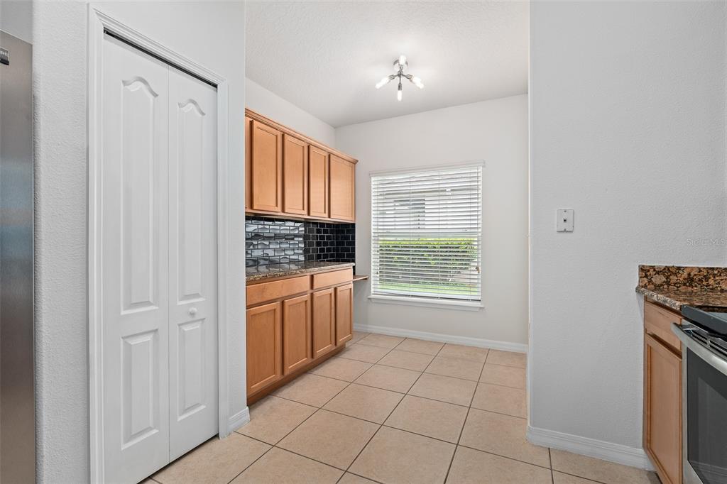 A kitchen area features light wood cabinets, a black tiled backsplash, and beige floor tiles — 5317 PEACH BLOSSOM BOULEVARD, PORT ORANGE, FL