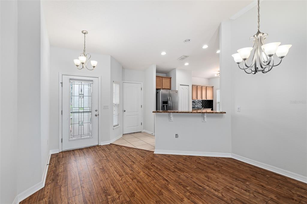 A dining area with wood-look flooring features a breakfast bar, kitchen, and two light fixtures — 5317 PEACH BLOSSOM BOULEVARD, PORT ORANGE, FL